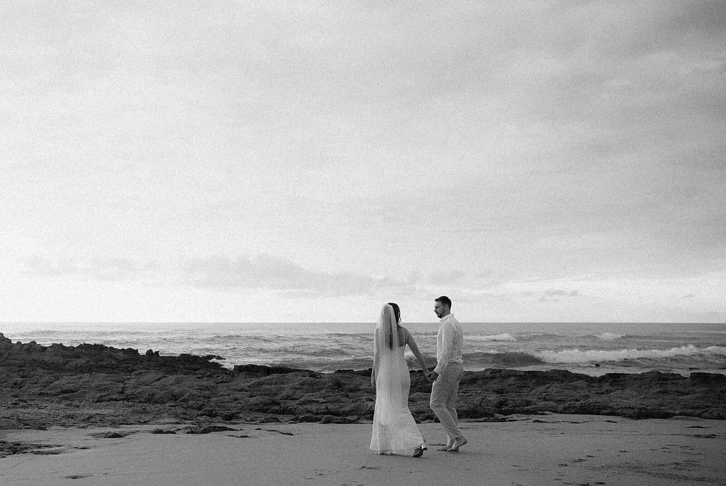 Black and white photo of a couple walking hand in hand on the beach at Hotel Nantipa, Santa Teresa, Costa Rica