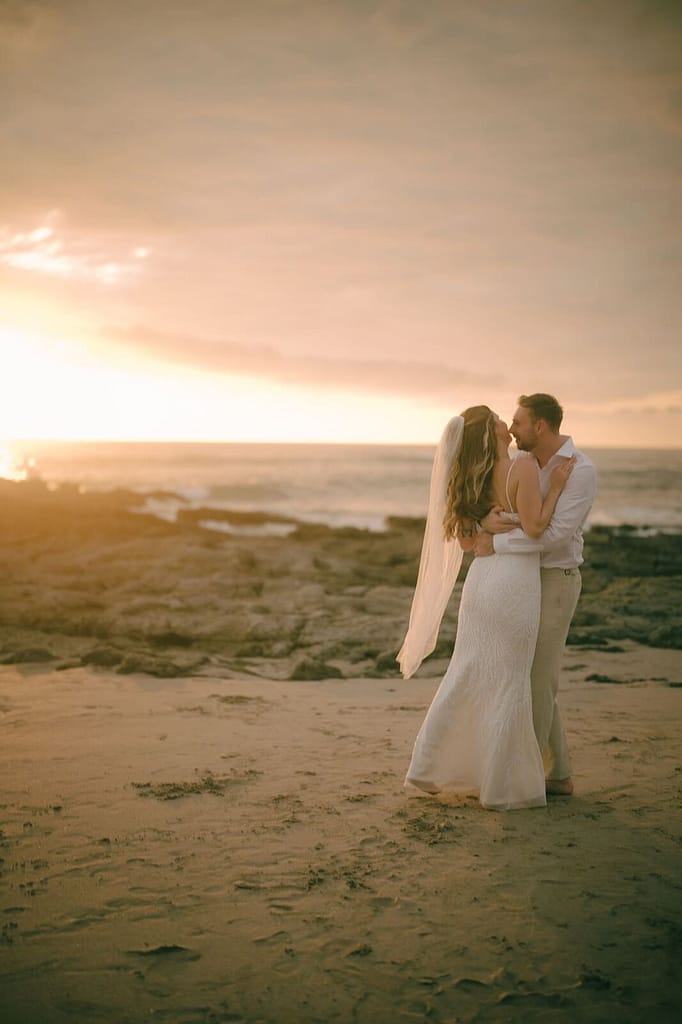 Wedding couple kissing on a rocky beach at sunset, Hotel Nantipa, Santa Teresa, Costa Rica