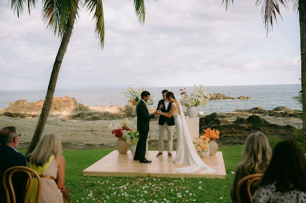 Couple exchanging vows on a platform above the ocean at a wedding near Montezuma, Costa Rica
