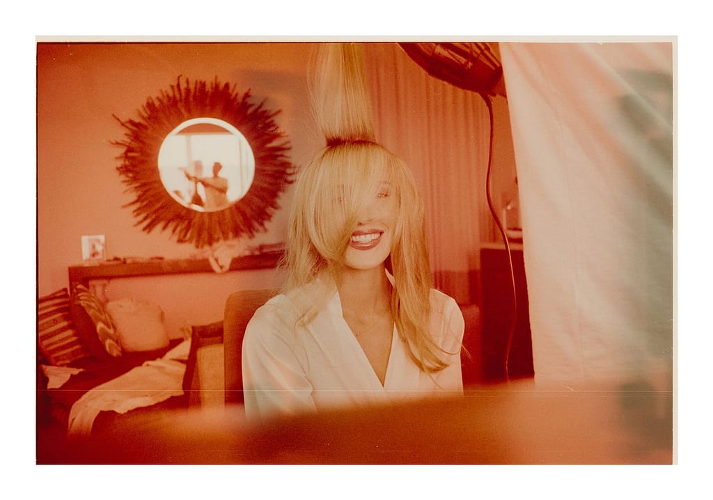 Warm orange film photograph of a bride in a white robe with a sunburst mirror behind her