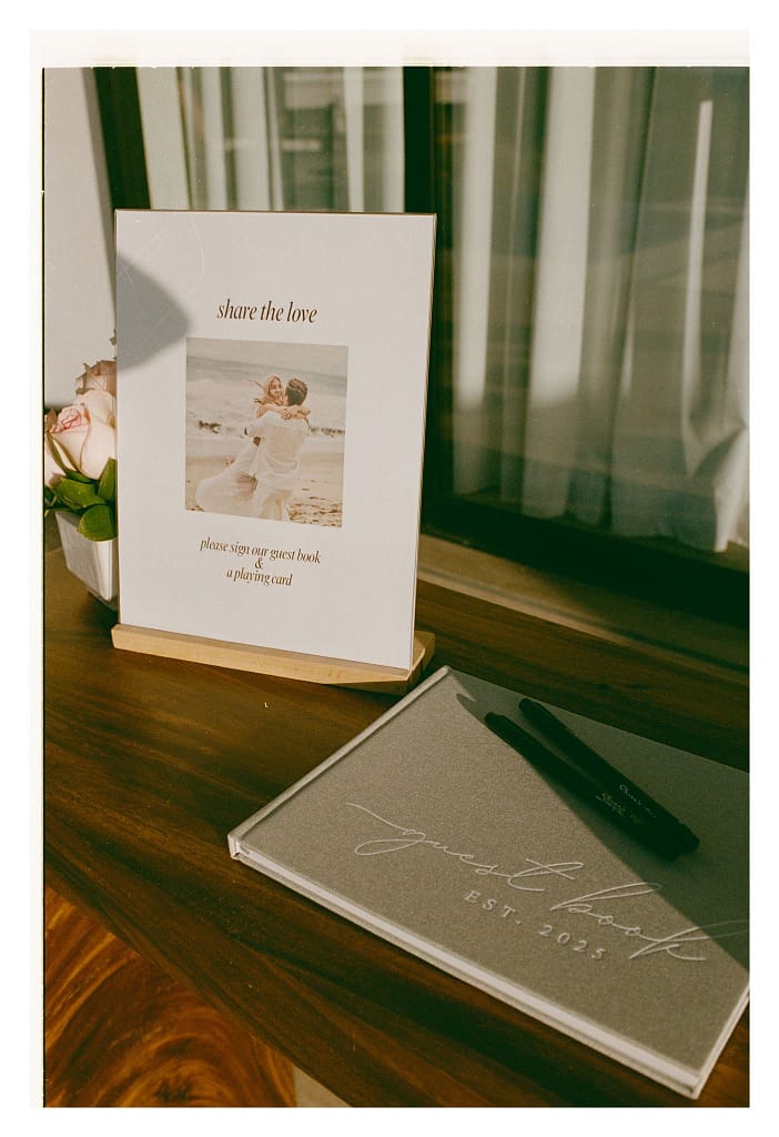 Film photograph of a guest book and a framed sign on a wooden table