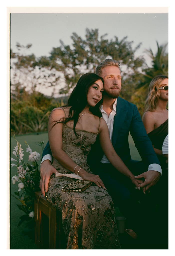 Film portrait of two wedding guests seated together at an outdoor ceremony