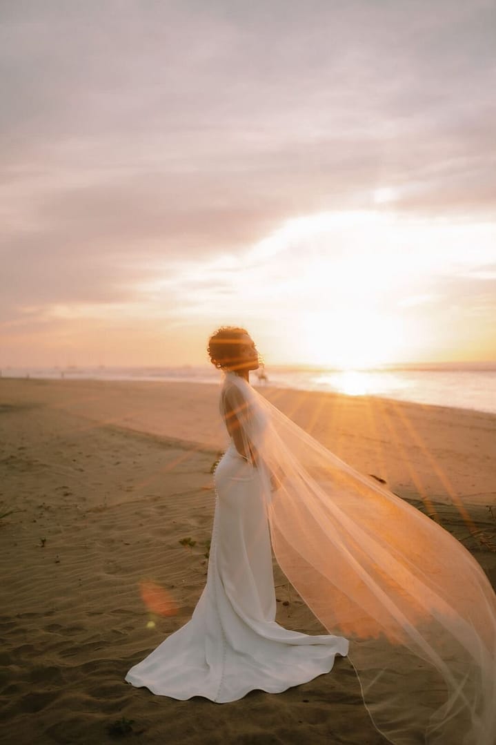 Bride's long veil blowing in the wind on a Costa Rica beach at sunset