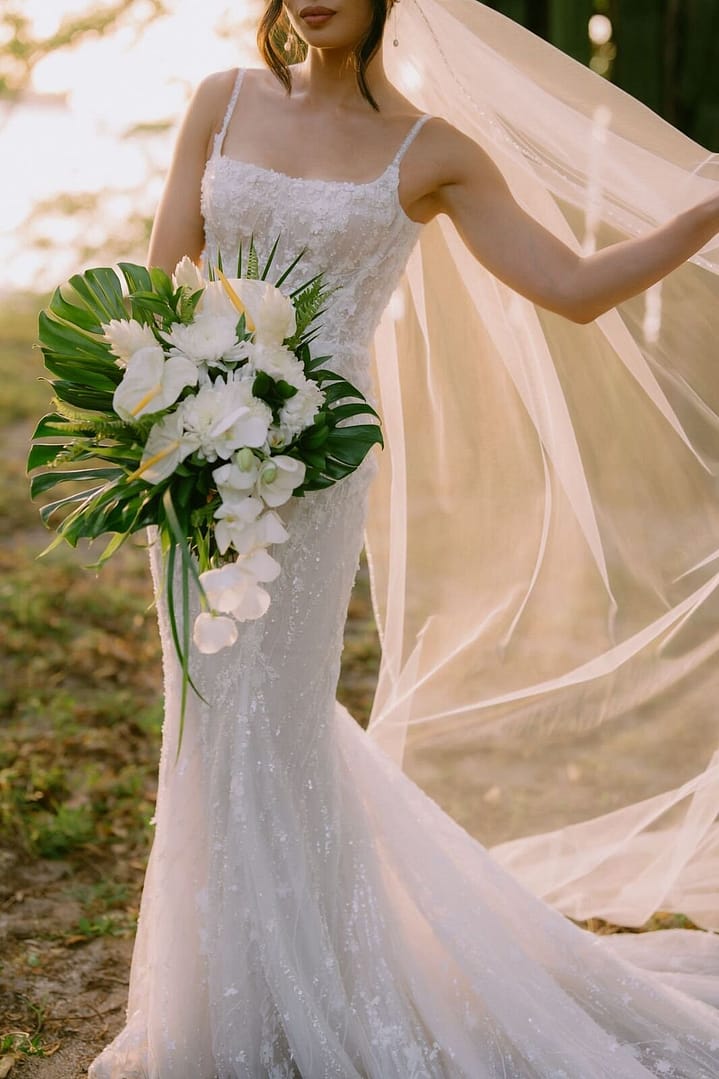 Bride holding a tropical white bouquet as the breeze lifts her veil, Costa Rica wedding