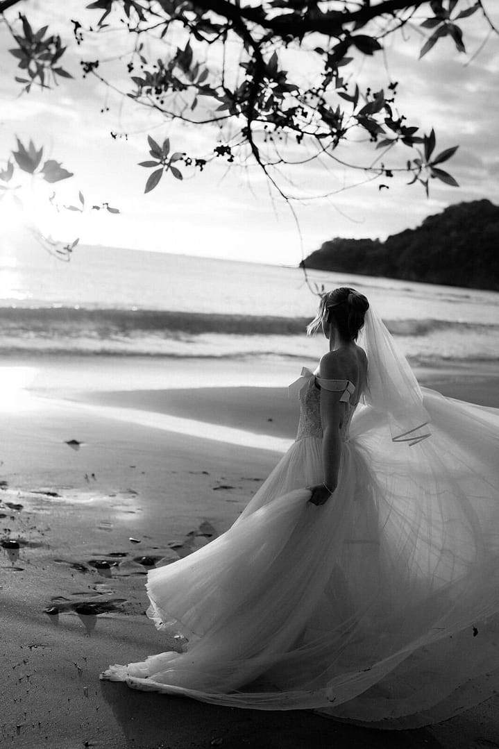 Black and white portrait of a bride twirling her gown on the beach at sunset, Costa Rica