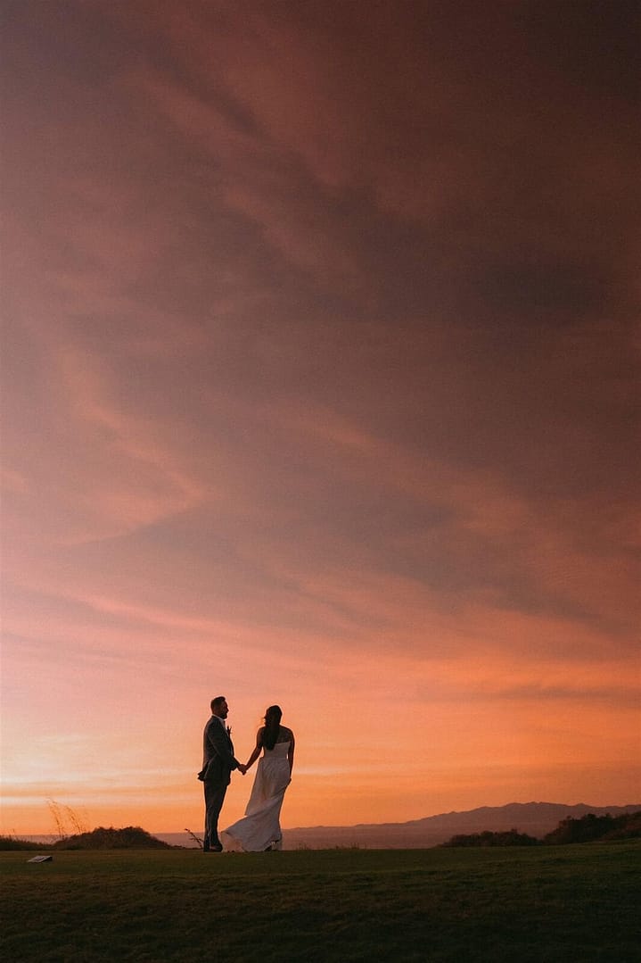 Newlyweds in silhouette holding hands under a fiery pink sunset sky, Costa Rica wedding photographer portrait