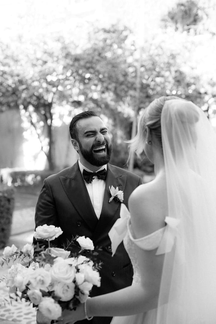 Black and white photo of a groom laughing joyfully beside his bride holding a bouquet, Costa Rica wedding